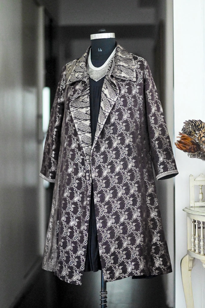 A long coat with a dark brown and beige floral damask pattern,